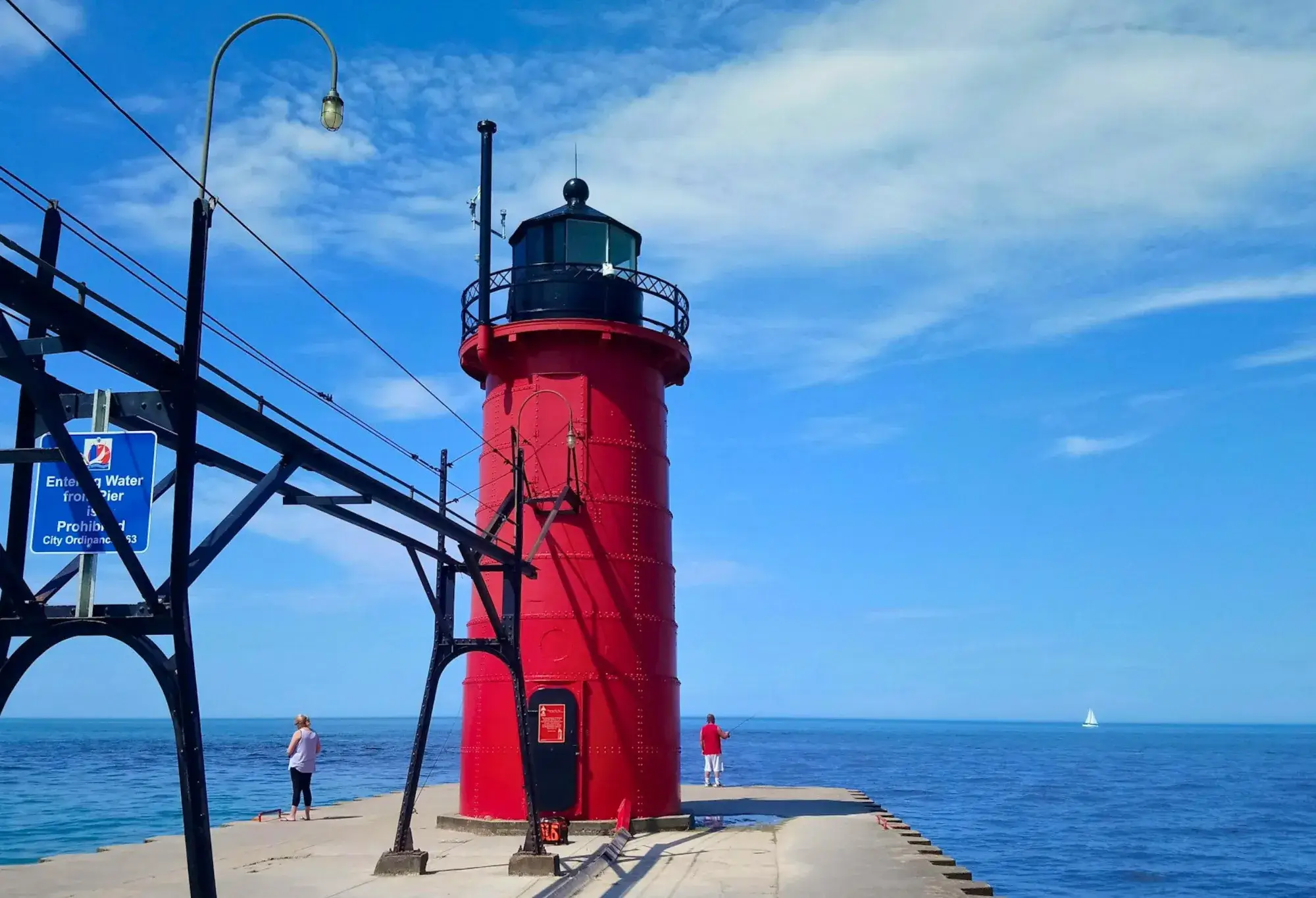 South Haven Lighthouse, a red metal tower with a black lantern room at the edge of a concrete pier.